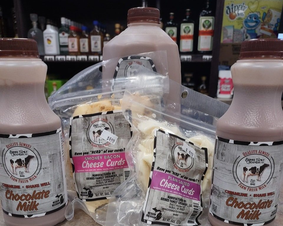 487564485_1188972206571657_873610618833205579_n Bottles of chocolate milk and bags of cheese curds from Brinks Family Creamery displayed on a store shelf, featuring flavors like Smoky Bacon and Plain Salted Cheese Curds.